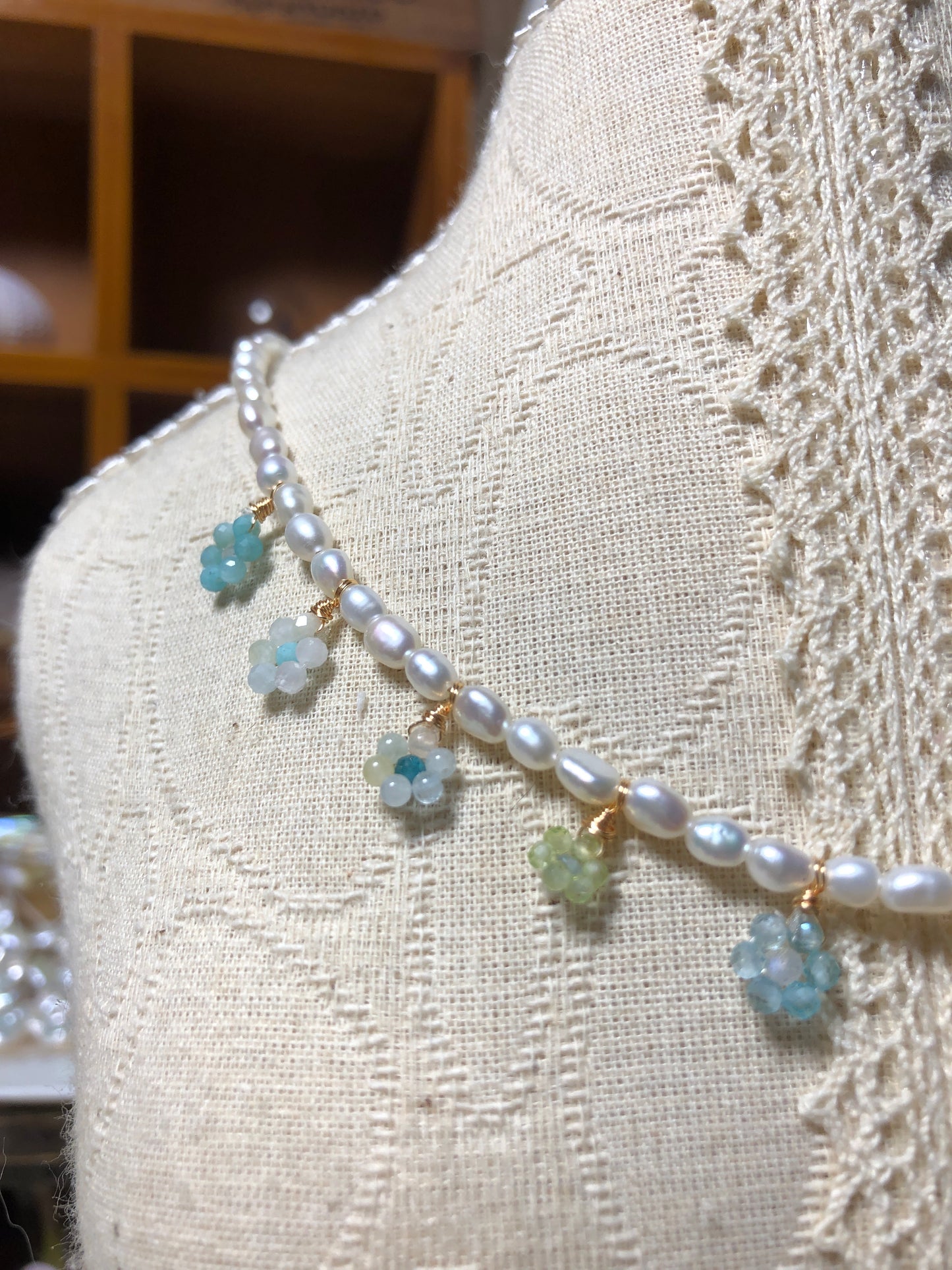 Full view of a nature-inspired handmade necklace showcasing floral gemstone pendants, freshwater pearls, and an adjustable 38cm + 5cm extension chain on a vintage-style mannequin.