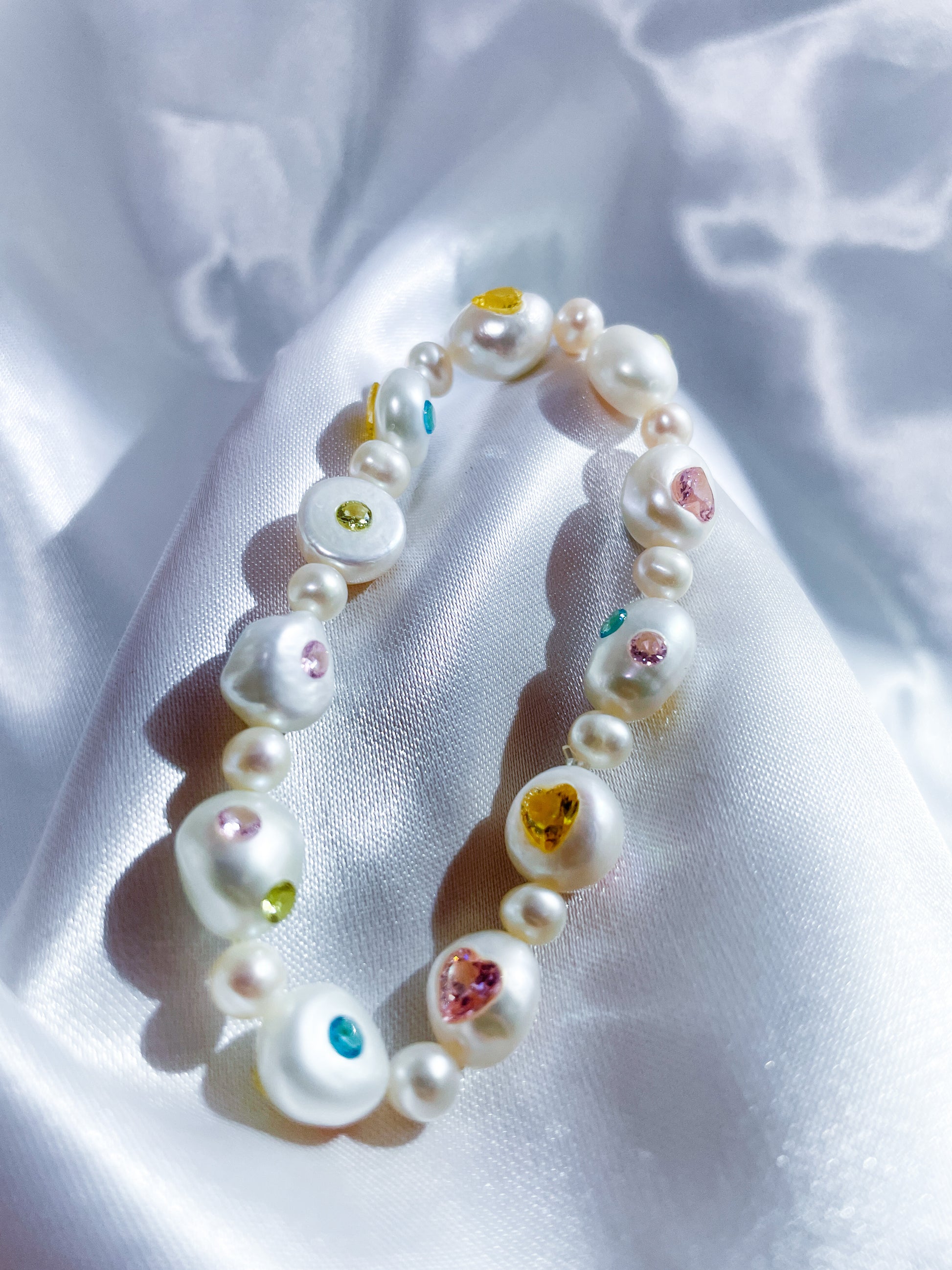 Model wearing a freshwater pearl bracelet with heart-shaped blue zircon gemstones, showing its elegant design.