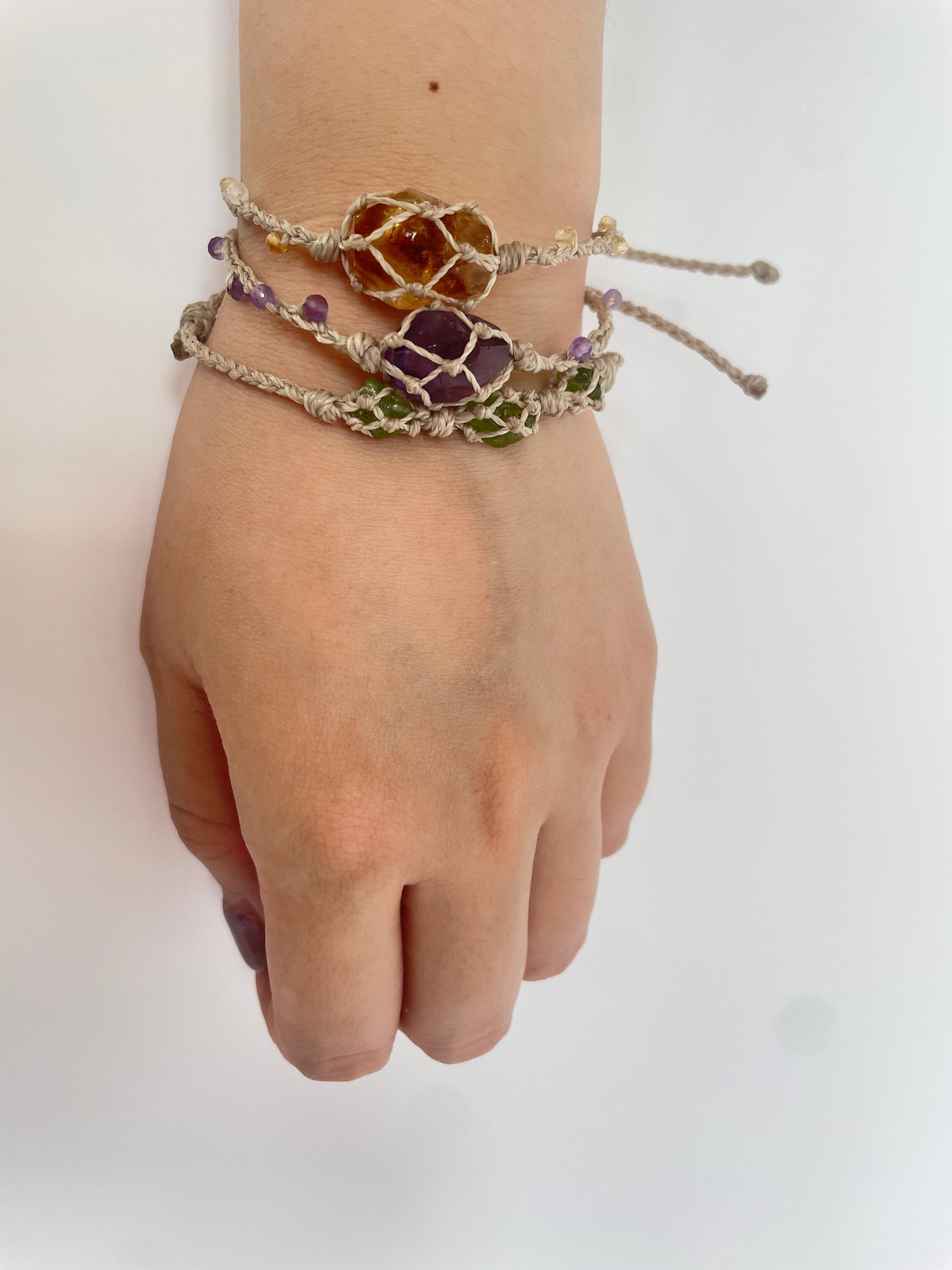 Handmade energy healing bracelet on wrist, showcasing Peridot, Amethyst, and Citrine gemstones.