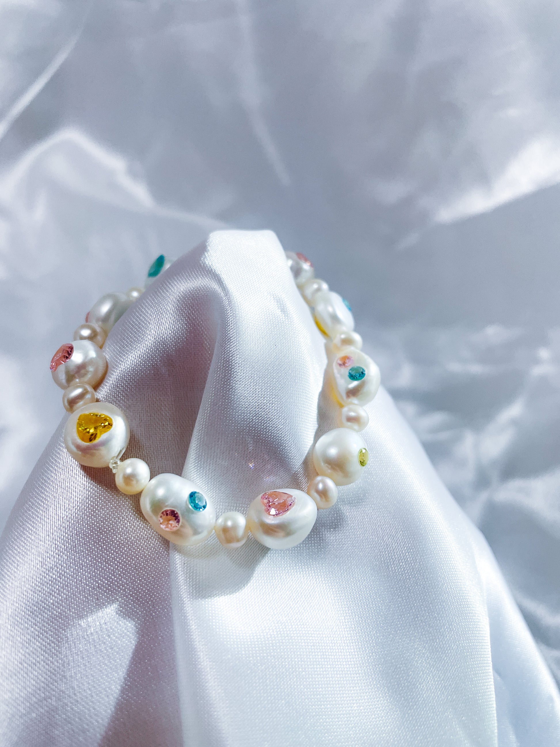 Freshwater pearl bracelet with customizable heart-shaped zircon gemstones in pink, yellow, and blue.
