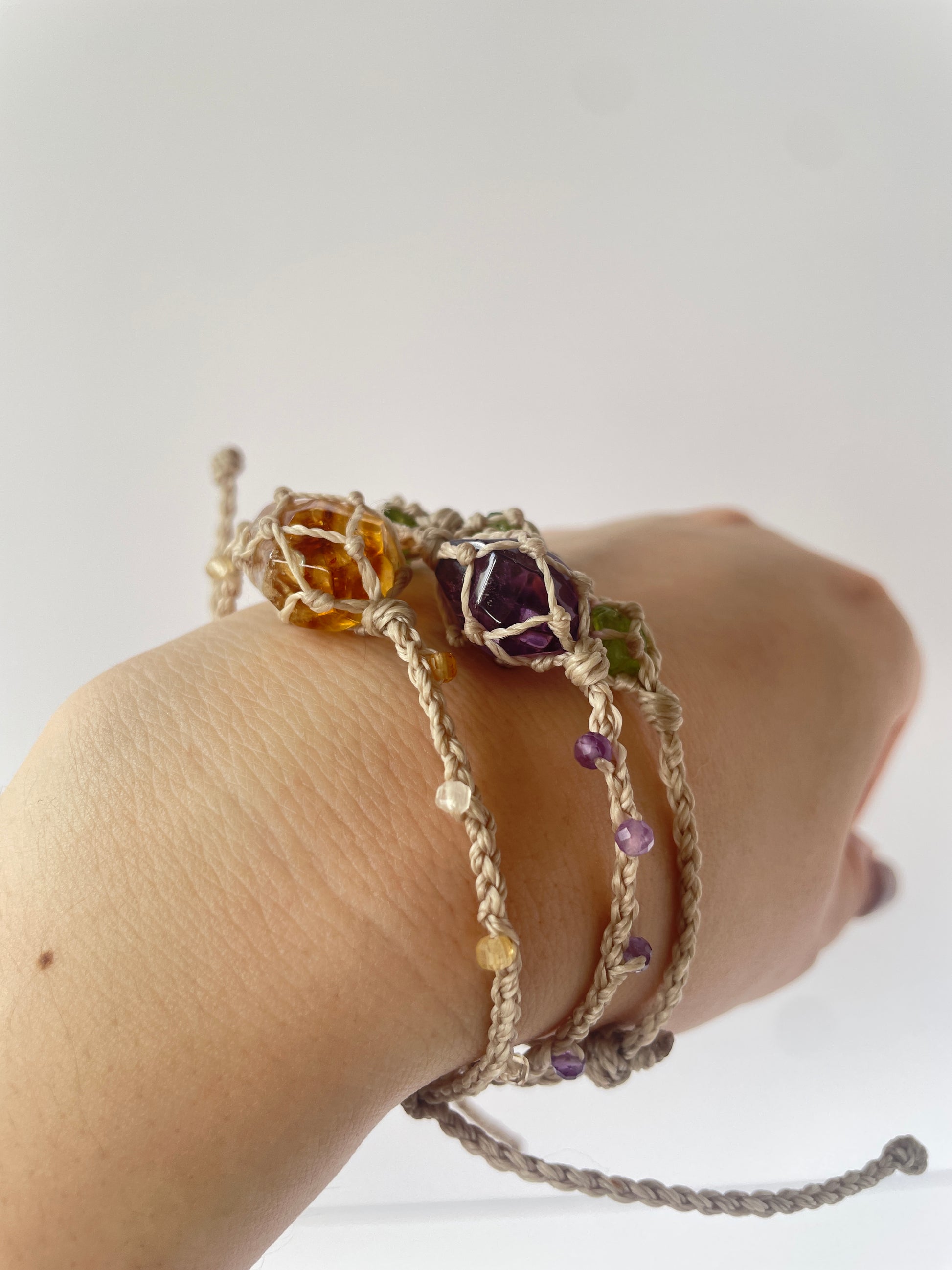 Stacked crystal healing bracelets with natural Citrine, Amethyst, and Peridot gemstones, handmade with wax cord.