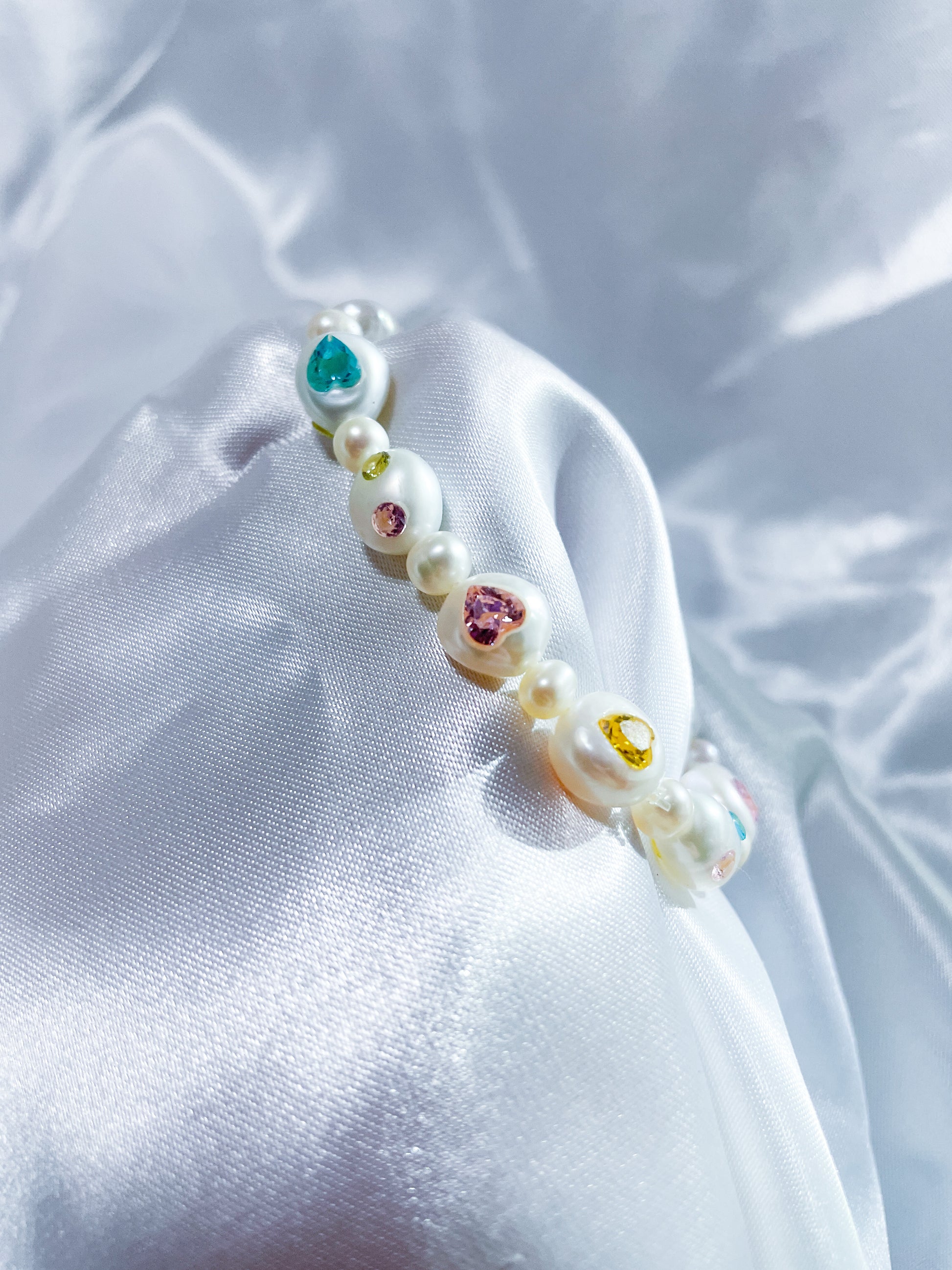 Side view of a natural freshwater pearl bracelet featuring hand-set heart-shaped zircon stones.