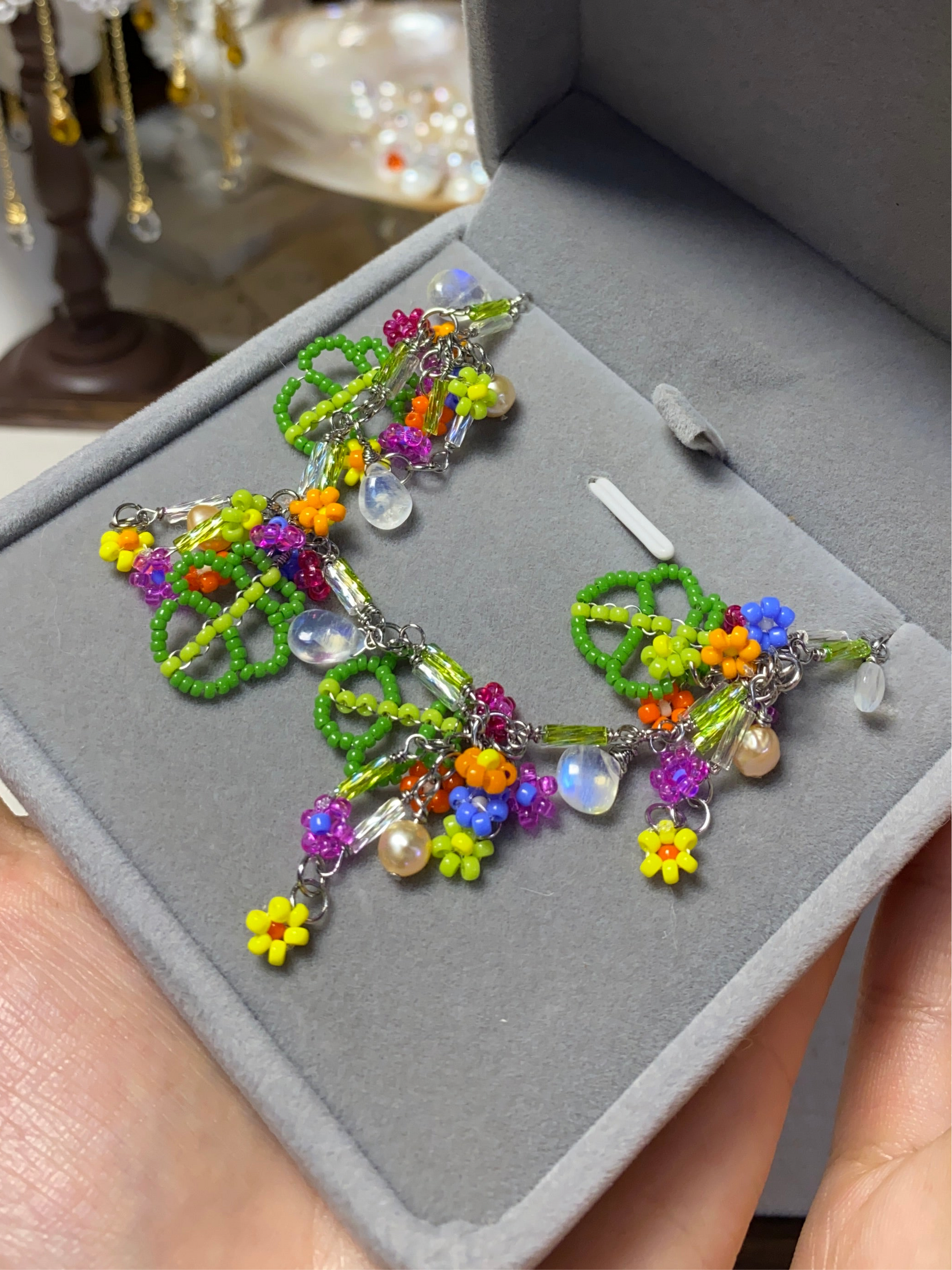 Handmade colorful floral bracelet with green leaves, vibrant beads, pearls, and moonstones, inspired by spring