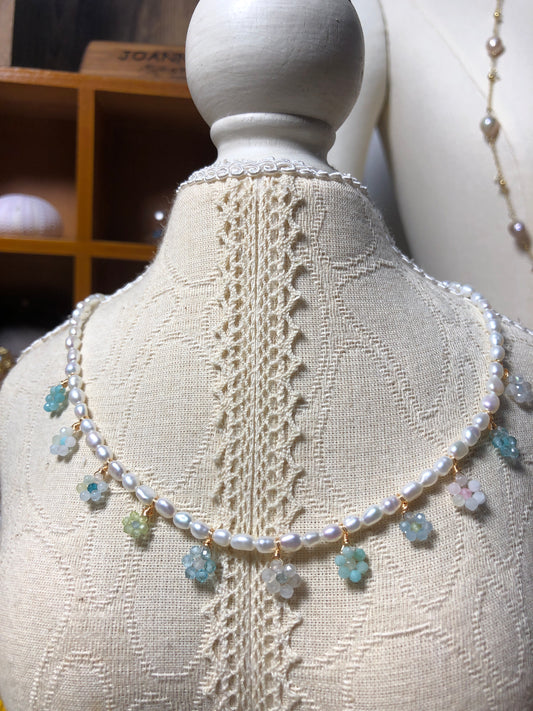 Close-up of a handmade floral crystal and pearl necklace featuring freshwater pearls, delicate flower-shaped pendants with Aquamarine, Peridot, and Moonstone gemstones, accented with 18K gold-plated titanium steel.