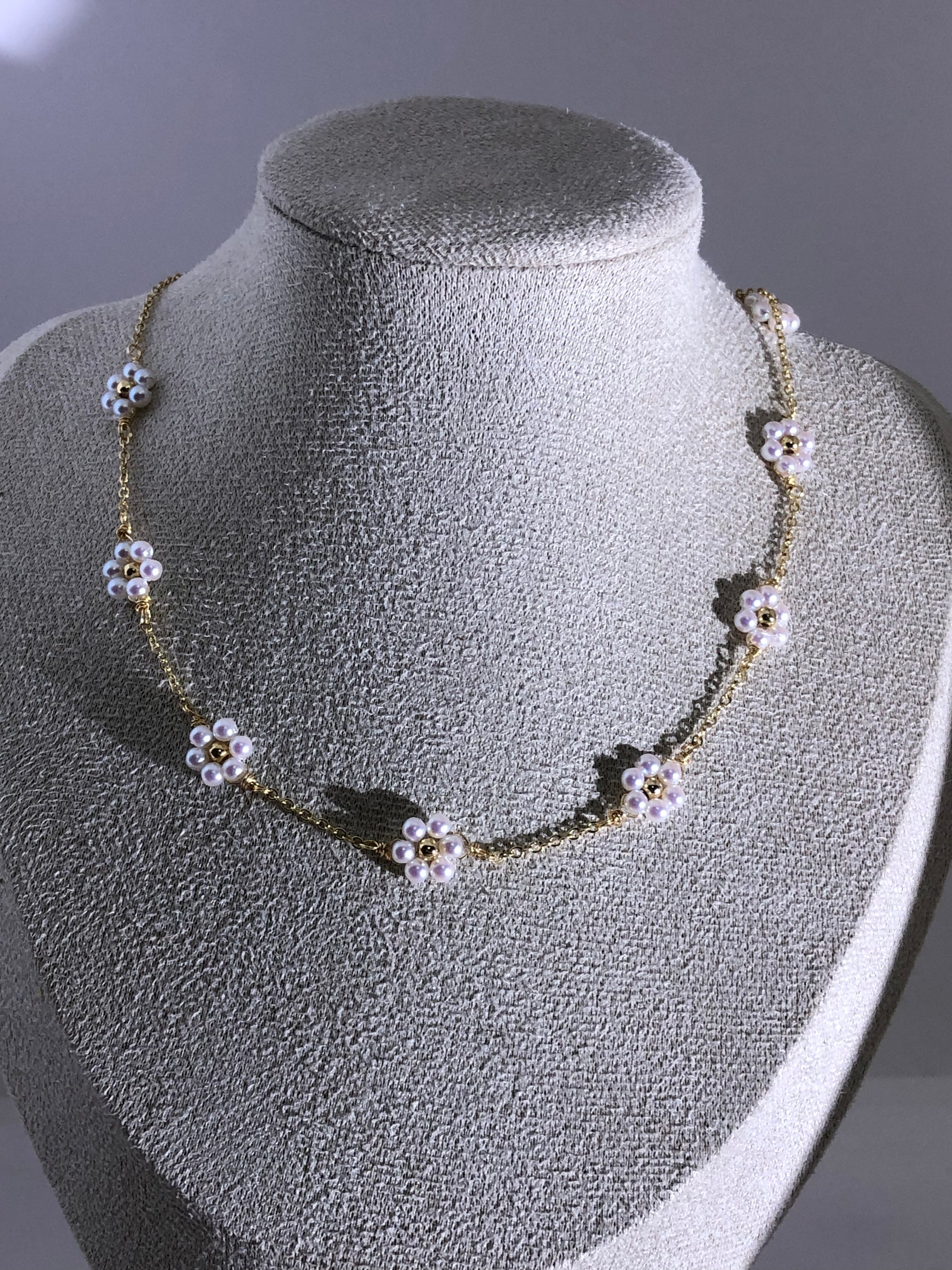 Handmade pearl flower necklace with 3mm artificial pearls and 18K gold-plated chain on display