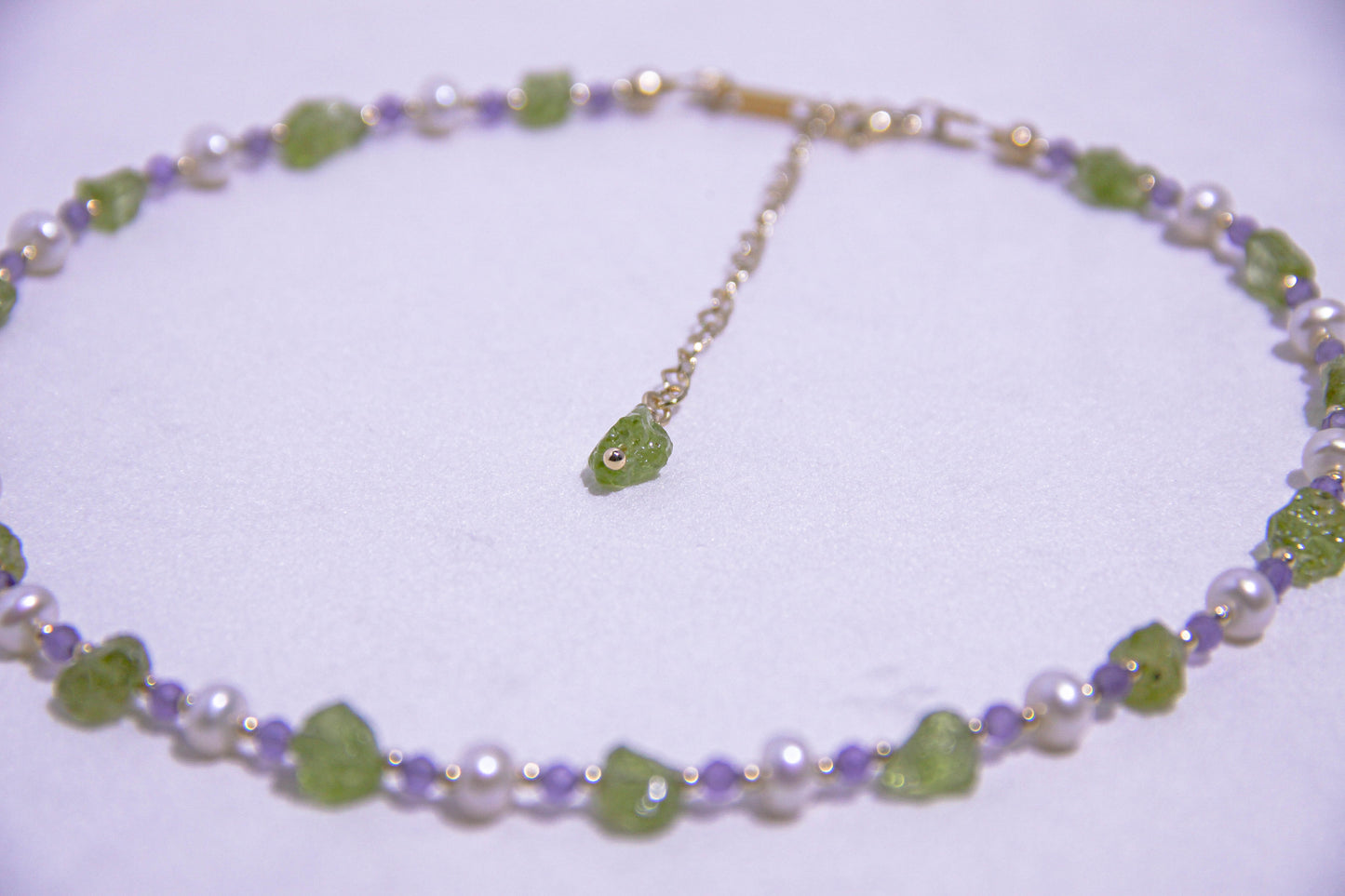 Close-up of raw Peridot gemstones with natural pearls and translucent Amethyst crystals