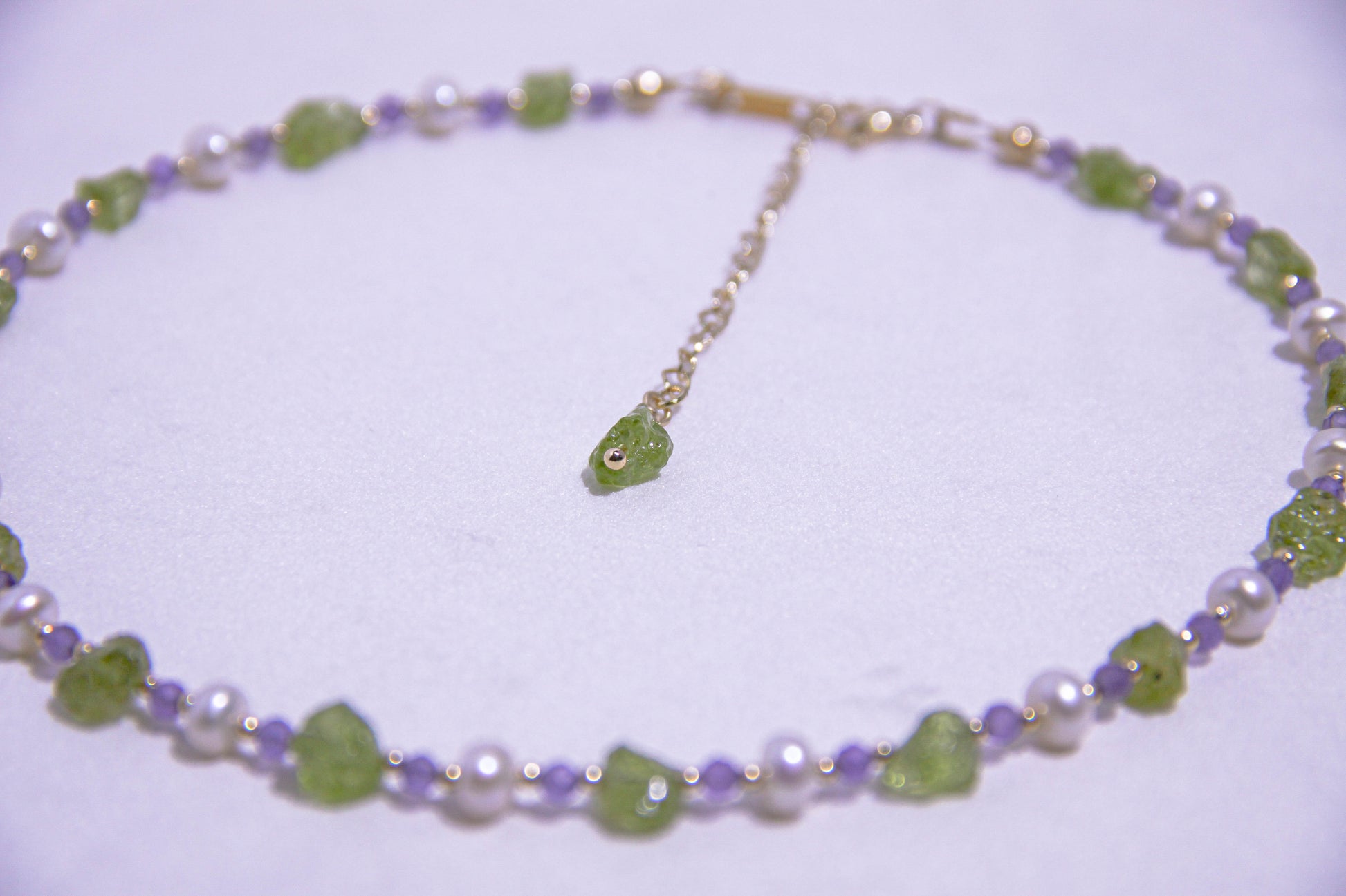 Close-up of raw Peridot gemstones with natural pearls and translucent Amethyst crystals