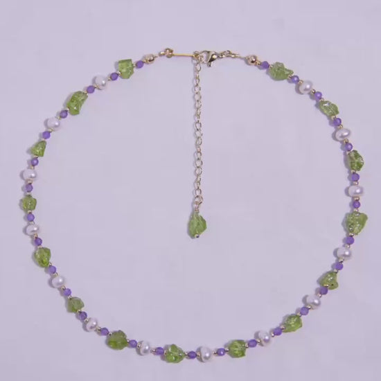 Side view of nature-inspired necklace showcasing vibrant green and purple gemstones with pearl details